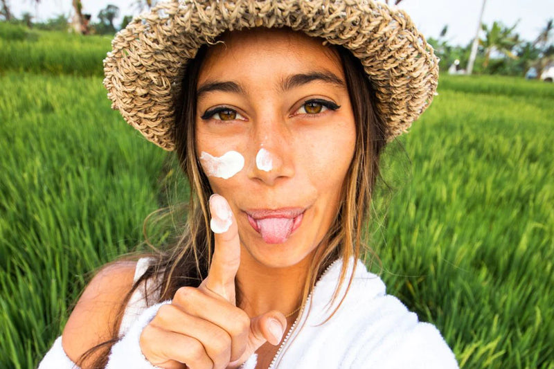 a woman looking at the camera with lotion on her face and finger